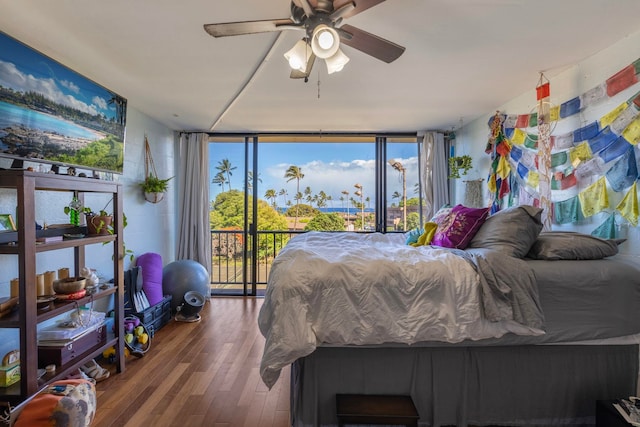 bedroom featuring ceiling fan, access to exterior, wood-type flooring, and multiple windows