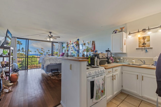 kitchen with white electric range oven, light hardwood / wood-style floors, white cabinetry, and sink