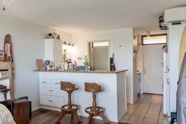 kitchen with kitchen peninsula, white cabinetry, and light hardwood / wood-style floors