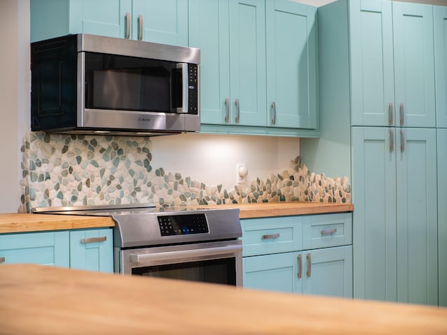 kitchen featuring blue cabinetry, wooden counters, and stainless steel appliances