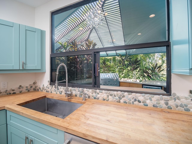 kitchen with butcher block countertops, sink, a chandelier, and blue cabinets