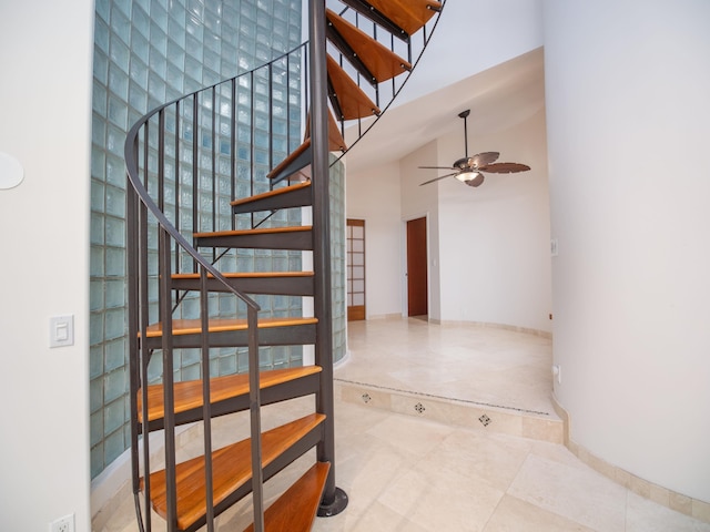 staircase with tile patterned floors, ceiling fan, and high vaulted ceiling