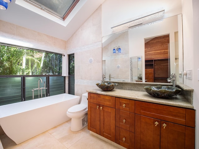 bathroom with vanity, vaulted ceiling, tile walls, toilet, and a tub