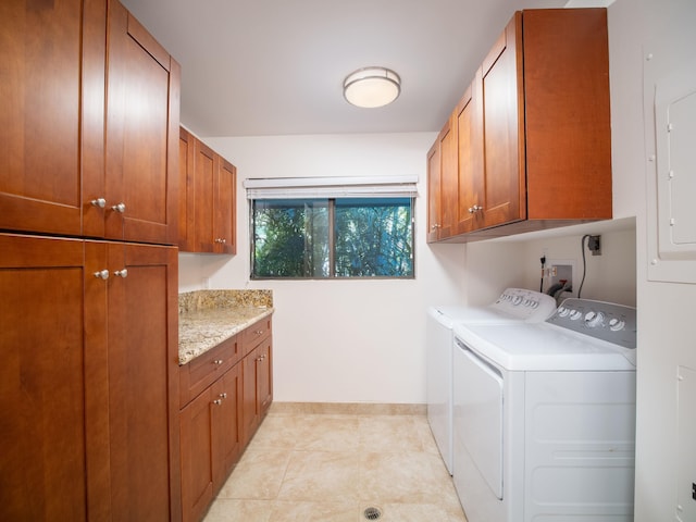 clothes washing area with electric panel, washer and clothes dryer, light tile patterned floors, and cabinets