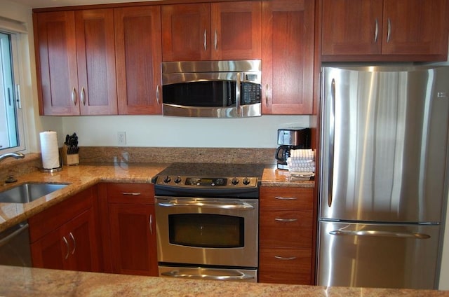 kitchen featuring light stone counters, appliances with stainless steel finishes, and sink