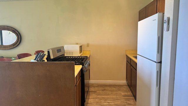 kitchen with white appliances and light hardwood / wood-style flooring