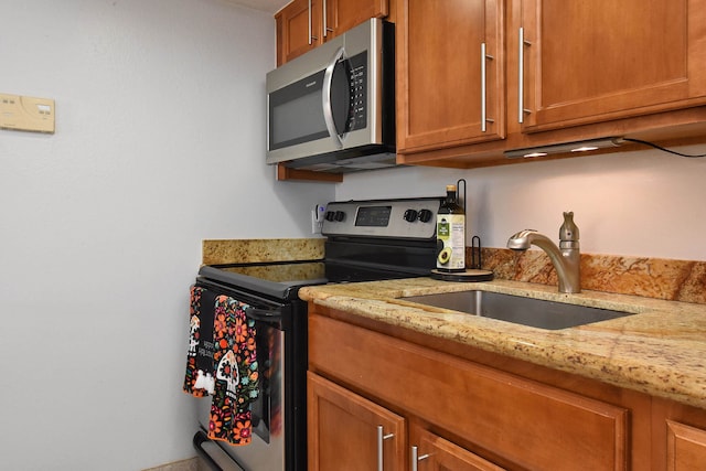 kitchen featuring light stone countertops, stainless steel appliances, and sink