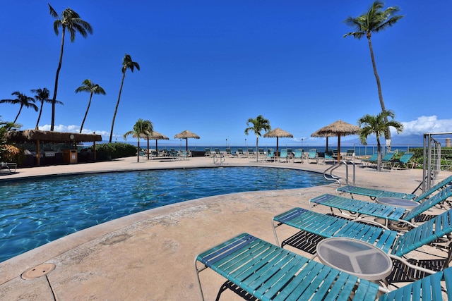 view of swimming pool with a water view and a patio area