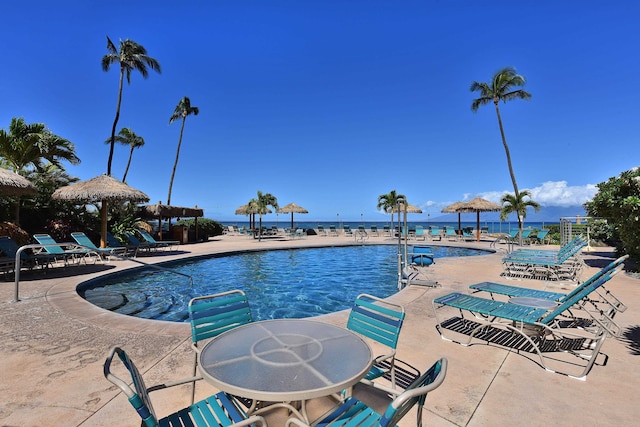 view of swimming pool featuring a patio and a water view