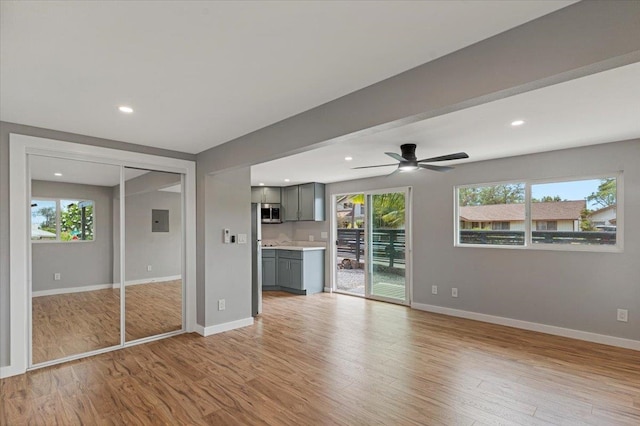 unfurnished living room with ceiling fan, light wood-type flooring, and a healthy amount of sunlight