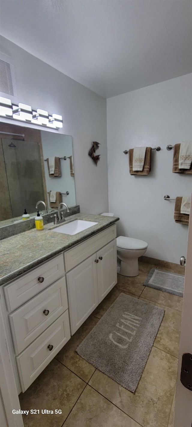 bathroom featuring tile patterned floors, toilet, a shower with door, and vanity