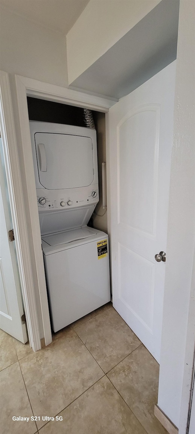 clothes washing area featuring stacked washing maching and dryer and light tile patterned floors