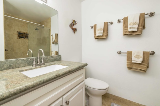 bathroom featuring vanity, toilet, and a tile shower