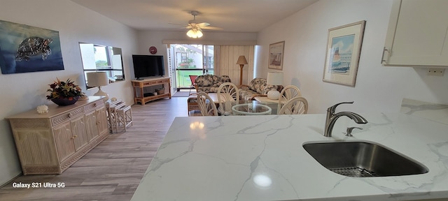 kitchen featuring ceiling fan, light stone countertops, sink, and light wood-type flooring