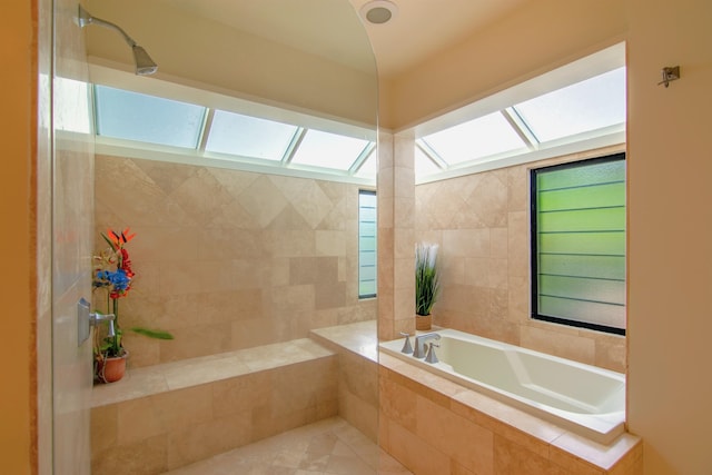 bathroom with plus walk in shower, a skylight, tile patterned flooring, and a healthy amount of sunlight