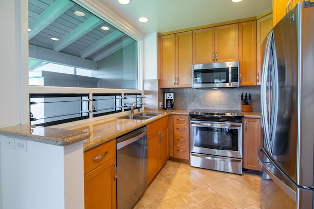 kitchen featuring light stone counters, kitchen peninsula, sink, lofted ceiling with beams, and appliances with stainless steel finishes