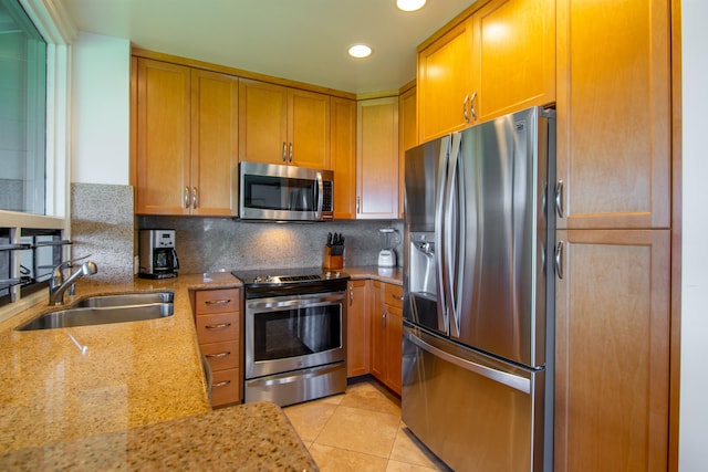 kitchen with light stone countertops, light tile patterned floors, backsplash, appliances with stainless steel finishes, and sink