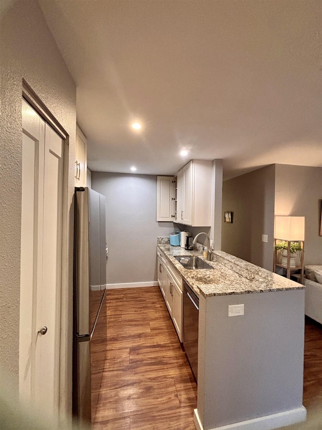 kitchen featuring a sink, light stone countertops, wood finished floors, stainless steel appliances, and white cabinets