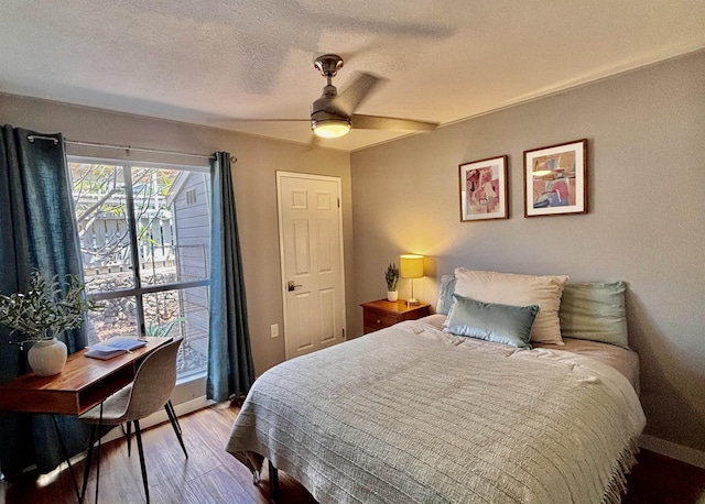 bedroom with a textured ceiling, ceiling fan, and wood finished floors