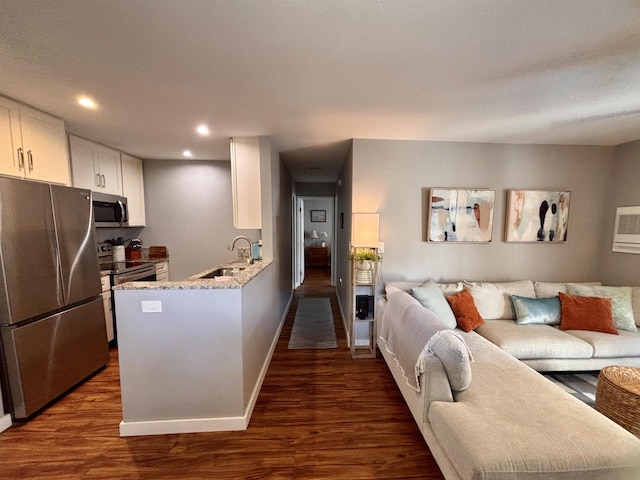 kitchen with a sink, white cabinetry, dark wood finished floors, open floor plan, and stainless steel appliances