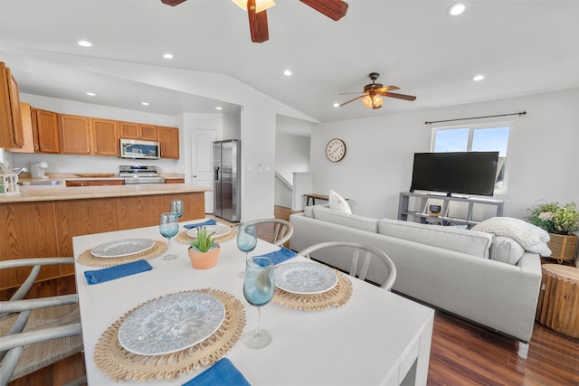 dining room with ceiling fan, dark wood-type flooring, and vaulted ceiling