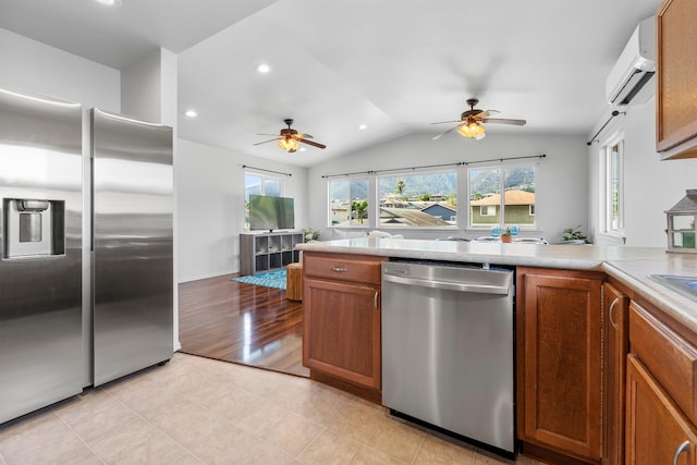 kitchen with ceiling fan, stainless steel appliances, vaulted ceiling, a wall unit AC, and light hardwood / wood-style flooring