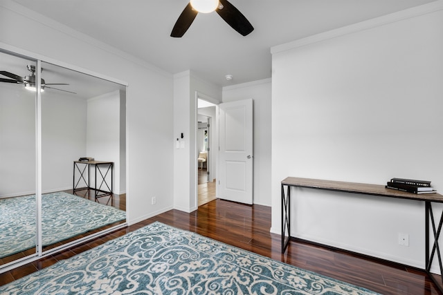 bedroom with a closet, ceiling fan, dark wood-type flooring, and crown molding