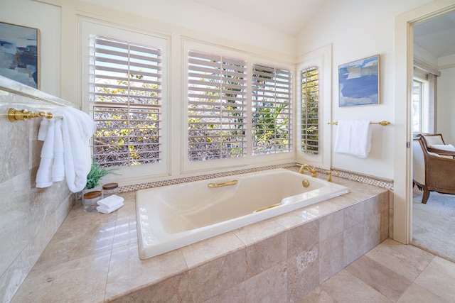 bathroom with vaulted ceiling, tile flooring, a relaxing tiled bath, and plenty of natural light