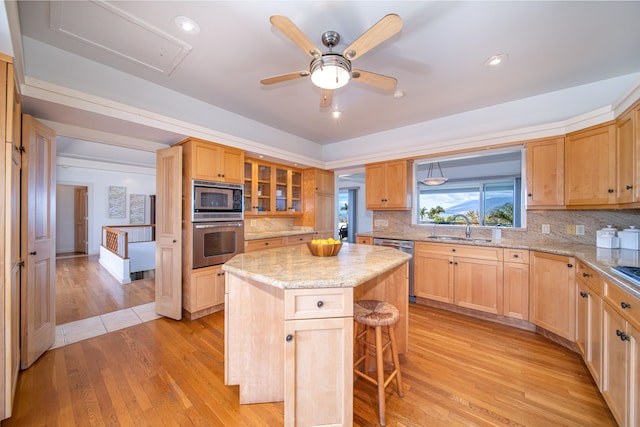 kitchen featuring ceiling fan, light hardwood / wood-style flooring, backsplash, stainless steel appliances, and a center island