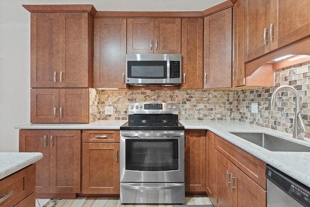 kitchen with light stone counters, sink, decorative backsplash, and appliances with stainless steel finishes