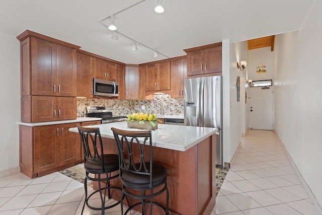 kitchen featuring light tile patterned flooring, a kitchen island, a breakfast bar area, decorative backsplash, and stainless steel appliances