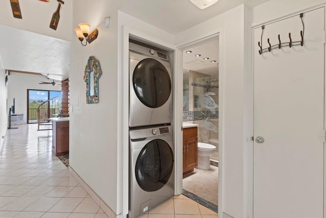 laundry room with stacked washer / dryer, light tile patterned floors, and ceiling fan