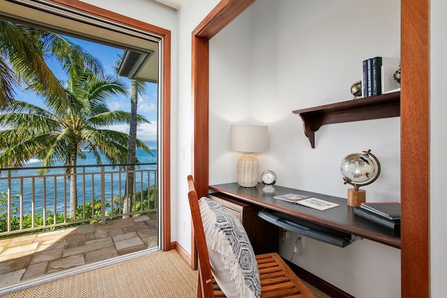 home office with a water view, baseboards, built in desk, and light colored carpet