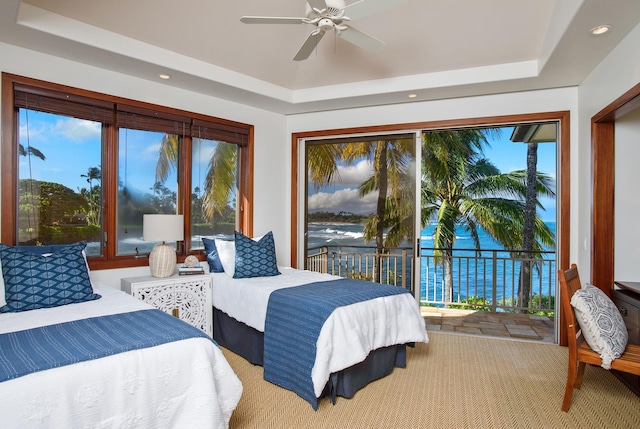 tiled bedroom with ceiling fan, a water view, access to exterior, and a raised ceiling