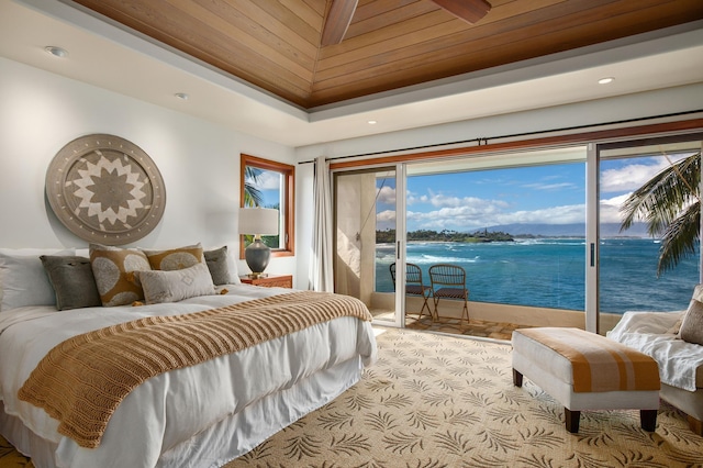 bedroom featuring access to exterior, recessed lighting, a raised ceiling, and a water view