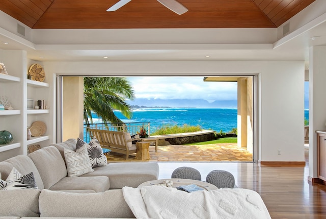 living area with built in features, a raised ceiling, a water view, wood finished floors, and wooden ceiling