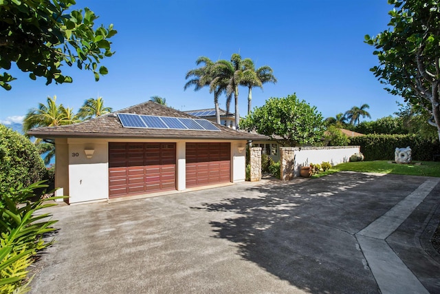 view of front of house with a garage, solar panels, fence, driveway, and stucco siding