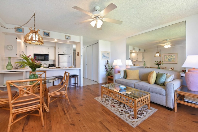 living room featuring ceiling fan, hardwood / wood-style floors, and a textured ceiling