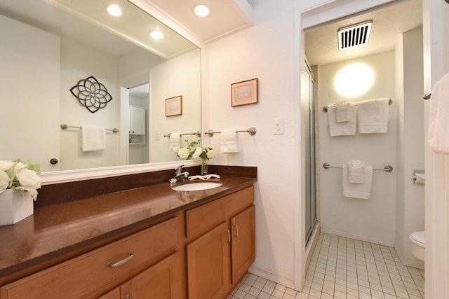 bathroom featuring tile flooring, toilet, vanity with extensive cabinet space, and an enclosed shower