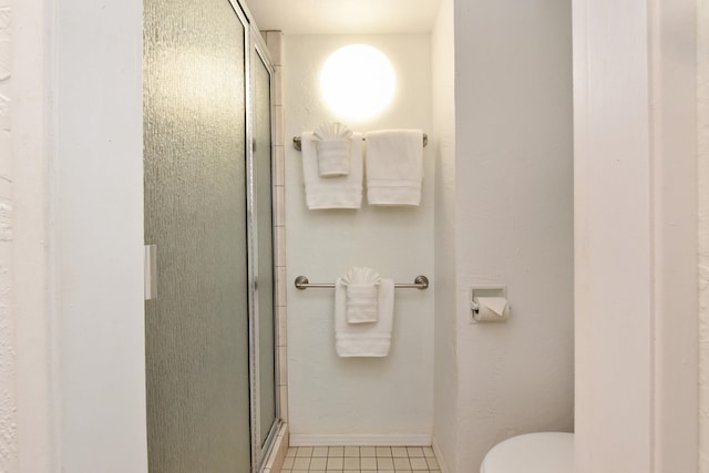 bathroom featuring tile flooring, toilet, and an enclosed shower