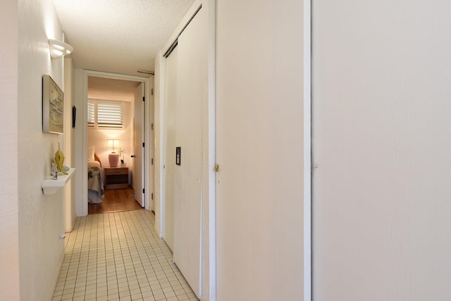 hallway featuring a textured ceiling and light tile floors