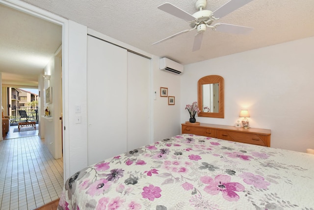 tiled bedroom with a textured ceiling, a closet, ceiling fan, and a wall mounted air conditioner