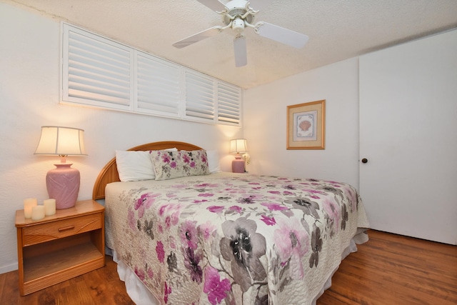 bedroom featuring dark hardwood / wood-style flooring, ceiling fan, and a textured ceiling