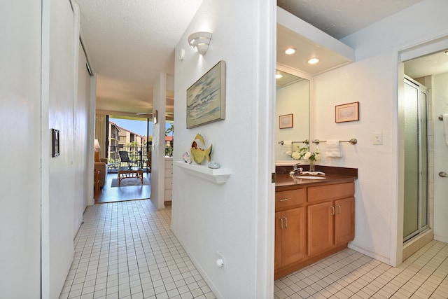 corridor with a textured ceiling, sink, and light tile flooring