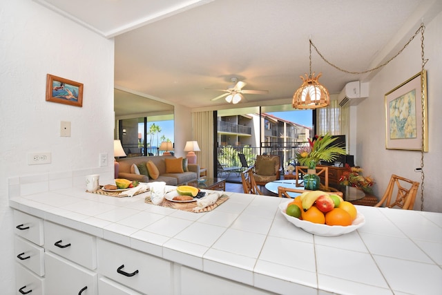 kitchen featuring ceiling fan, tile countertops, decorative light fixtures, kitchen peninsula, and white cabinets