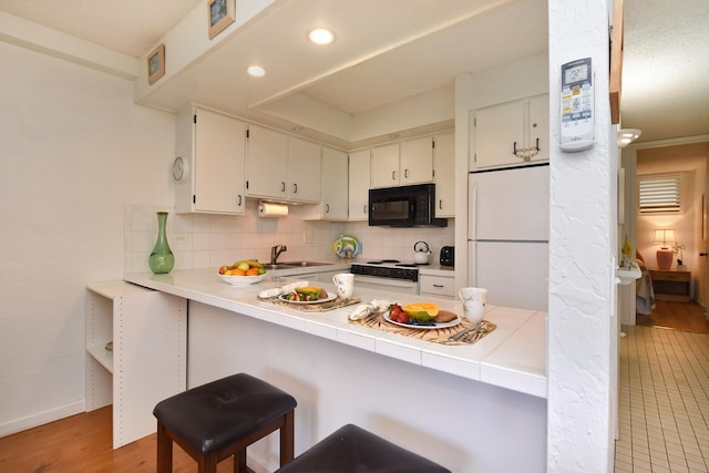 kitchen featuring sink, backsplash, light hardwood / wood-style flooring, and white appliances