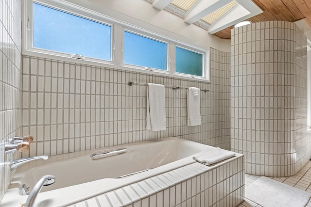 bathroom with tile patterned floors, a relaxing tiled tub, and a skylight