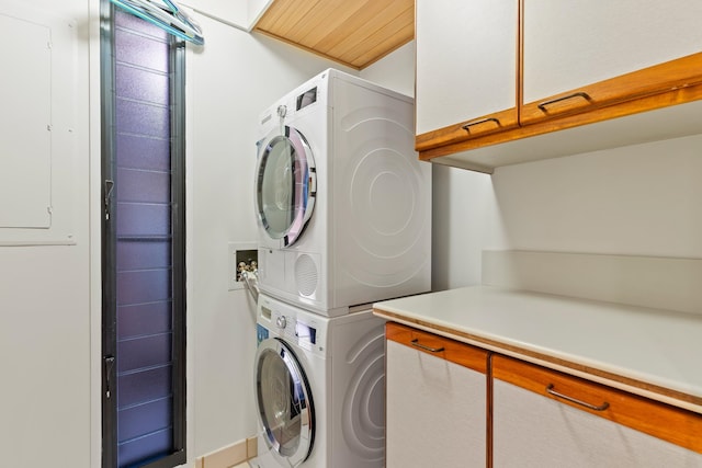 washroom featuring cabinets, stacked washer / dryer, and wooden ceiling