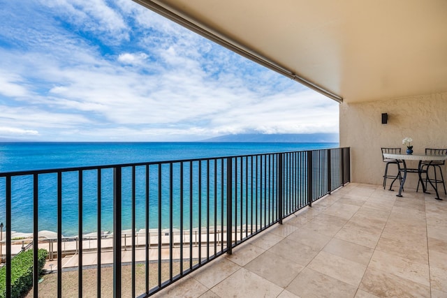 balcony with a water view and a view of the beach