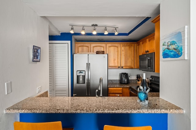 kitchen featuring black appliances, a kitchen bar, rail lighting, kitchen peninsula, and dark stone counters